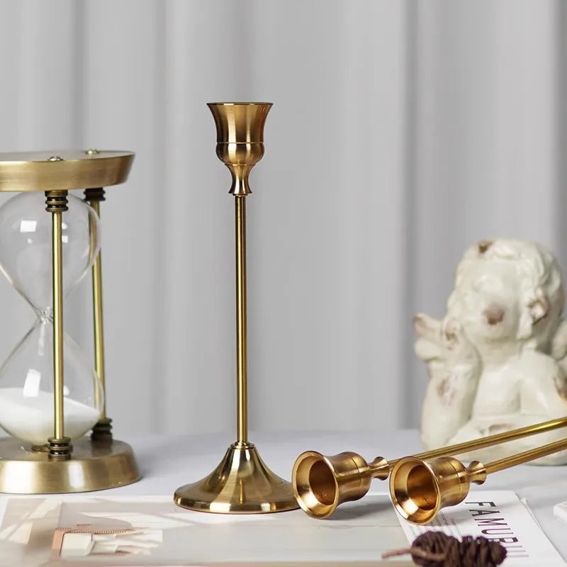 Kit 3 castiçais vintage dourados em alturas diferentes sobre mesa decorada”