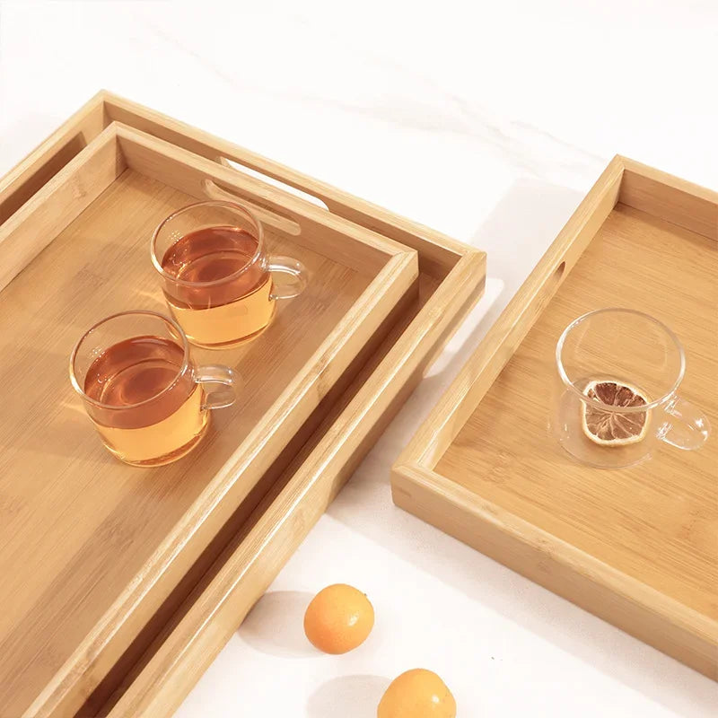 Bandeja retangular de bambu natural com alças vazadas laterais sobre mesa de madeira, ideal para servir e organizar

