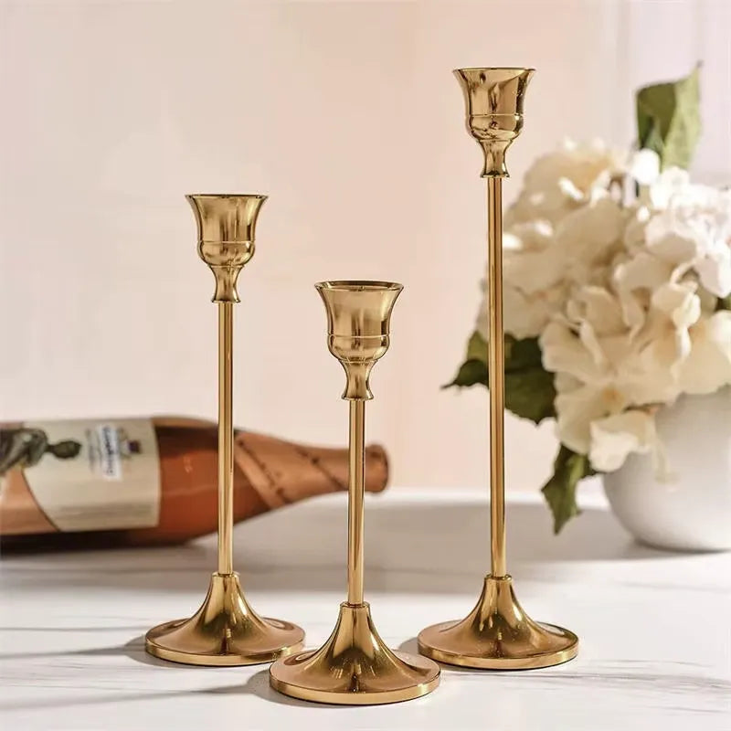 Kit 3 castiçais vintage dourados em alturas diferentes sobre mesa decorada”