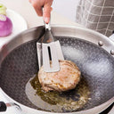 Pinça 3-em-1 em aço inox segurando e virando bife na frigideira – Casa Splendida