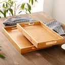 Bandeja retangular de bambu natural com alças vazadas laterais sobre mesa de madeira, ideal para servir e organizar

