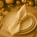 Anéis de guardanapo dourados minimalistas em mesa posta de réveillon elegante, com guardanapo de linho claro, pratos brancos com filete dourado e iluminação quente Casa Splendida